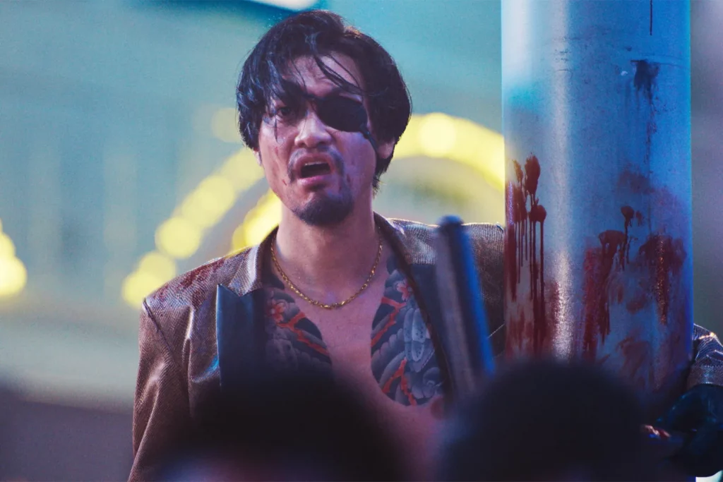 Munetaka Aoki's Majima looking towards the camera, holding onto a blood-stained lamp post